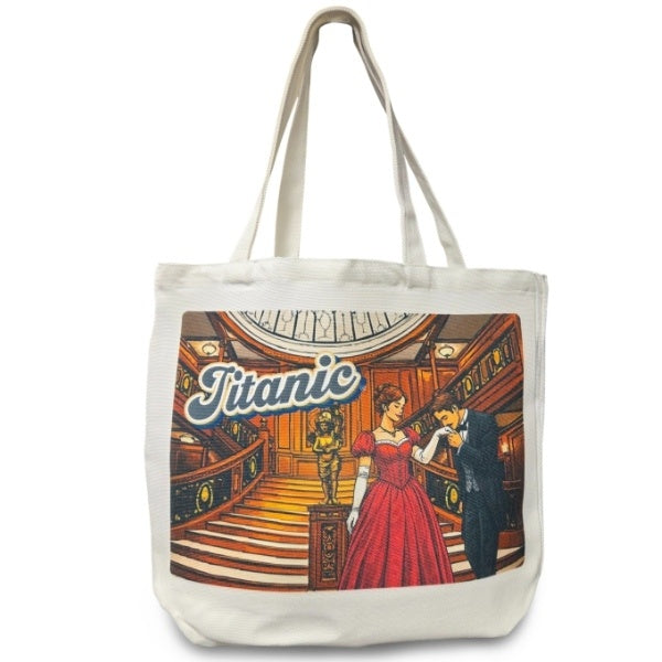 A white canvas tote bag with handles printed with an image of a gentleman kissing a woman's glove on the grand staircase under the word "Titanic".