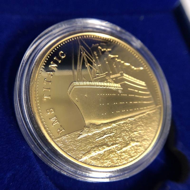 Gold color Titanic coin in acrylic protector case with embossed image of ship.