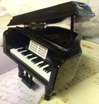 A black glossy grand piano miniature with its lid propped open, it is an ornament.