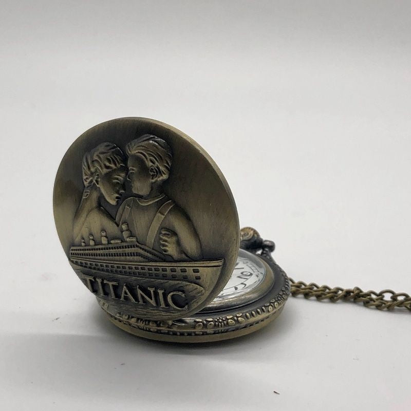 Antique brassy pocket watch with embossed image of a couple embracing above the Titanic.