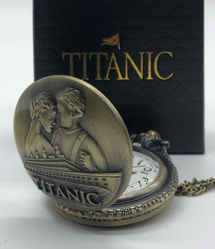 Closeup of front of pocket watch necklace showing a couple embracing above the Titanic. The long necklace chain is thinner than a pocket watch chain.