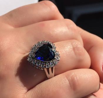 BLUE CRYSTAL HEART RING SURROUNDED IN A SPARKLING CUBIC ZIRCONIUM SETTING